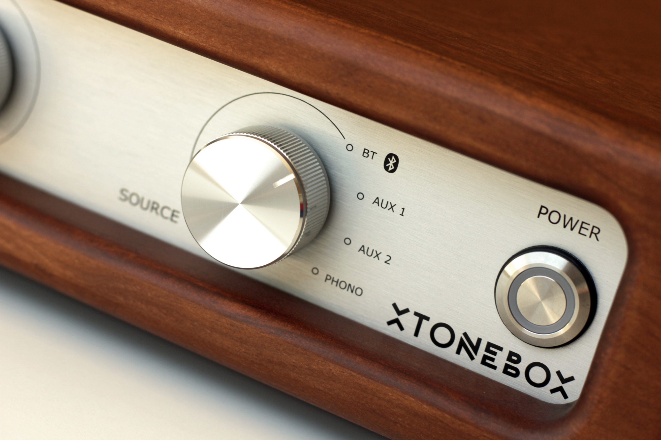 Audio amplifier control knob close-up on silver panel with source and aux labels