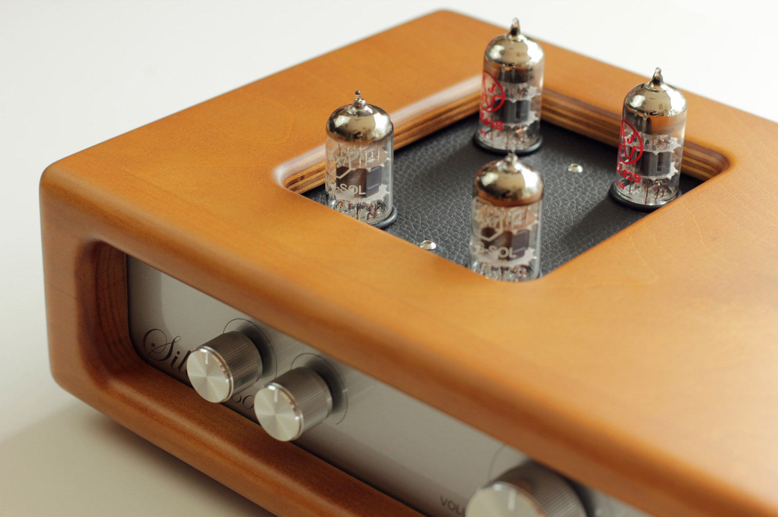 Wooden audio amplifier top with five vacuum tubes in a black perforated cover