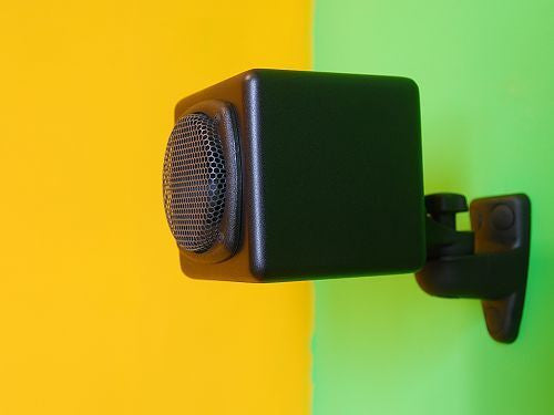 Black square speaker with circular grille mounted on a bracket