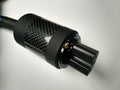 Black carbon-fiber IEC plug with gold contact pin and textured grip ring