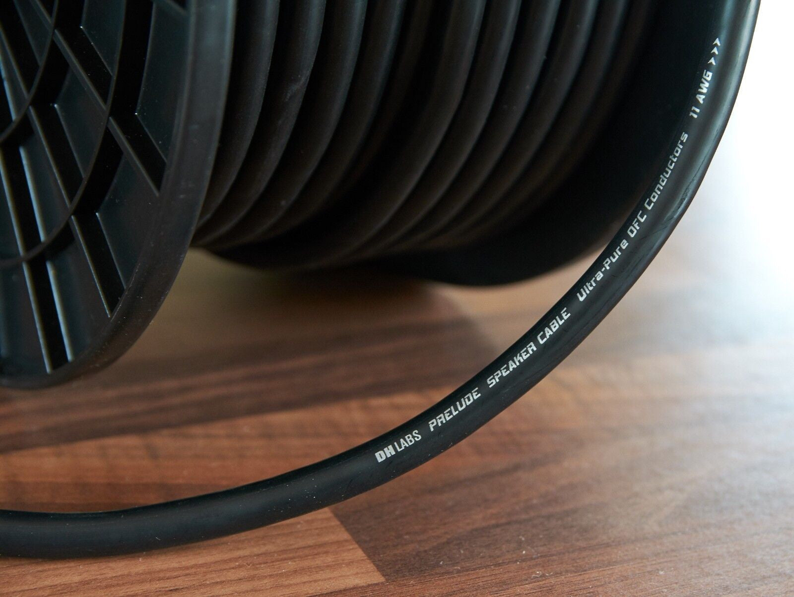 Black speaker cable with printed text along jacket, partly uncoiled on surface.