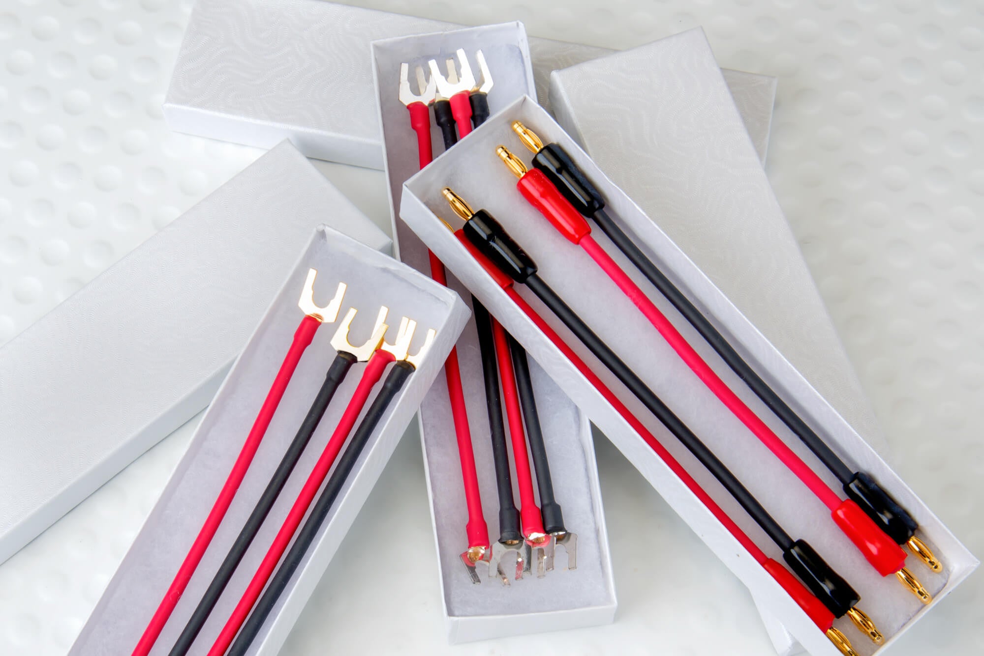 Jumper cable set with red and black wires and gold spade clamps in storage box