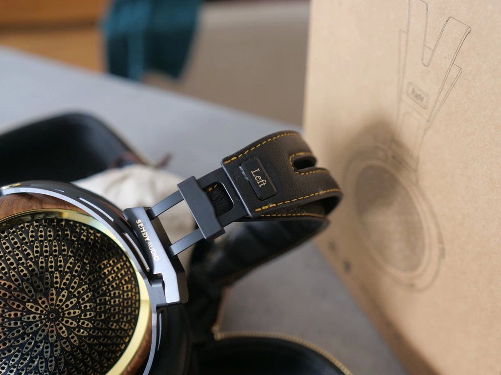 Left earcup of black headphones with gold-edged stitching on headband