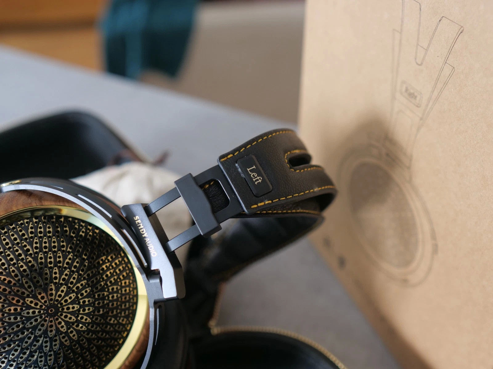 Left earcup of black headphones with gold-edged stitching on headband