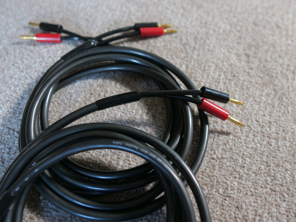 Black loudspeaker cable coil with red and gold banana plug connectors, multiple ends