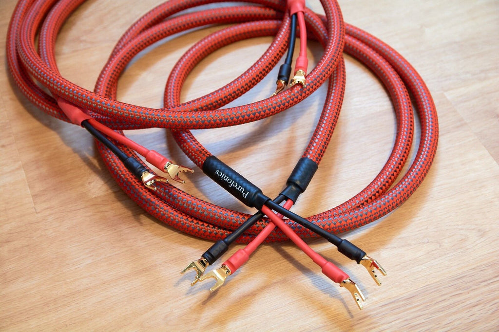 Red braided audio cables with gold-plated banana plugs and black connector ends in pairs