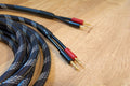 Braided black and blue audio cable with gold banana plugs and red accents