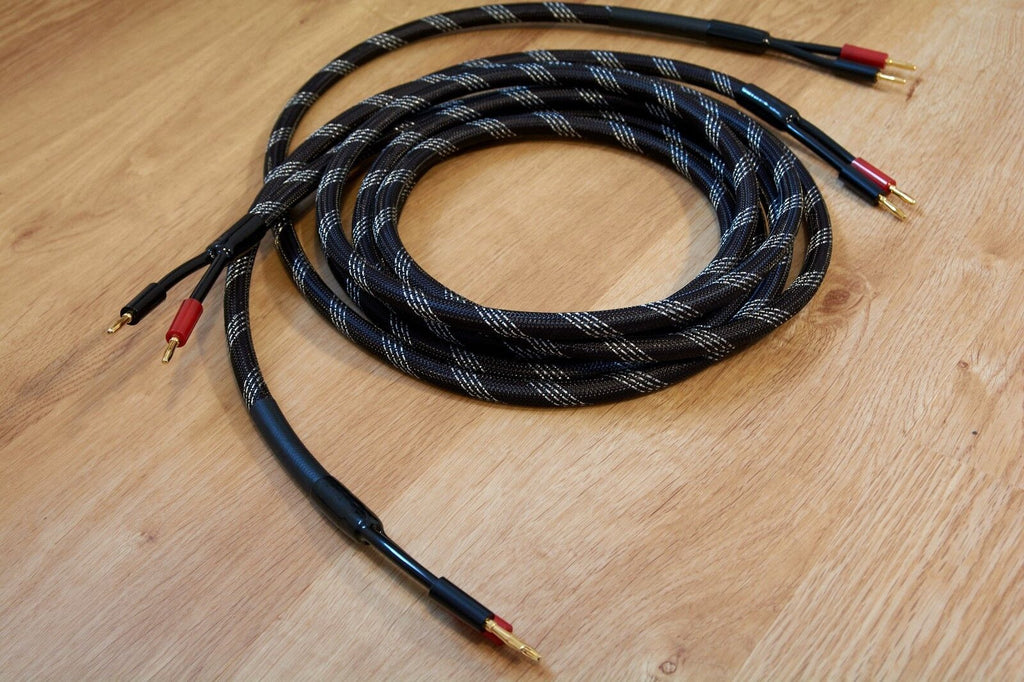 Coiled braided audio cable with black and silver threads and gold banana plugs