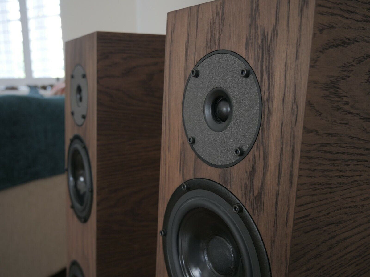 Chocolate-brown speaker front close-up with black woofer and centered tweeter in circular plate