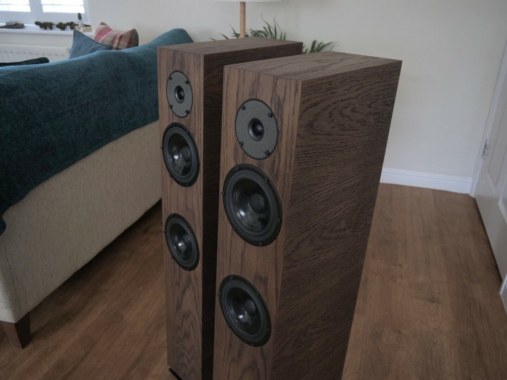 Chocolate-brown floorstanding speaker pair angled toward camera, with black woofers and tweeters