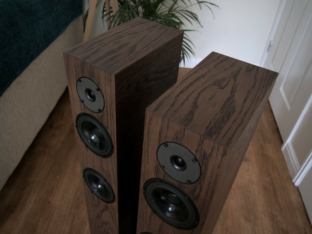 Chocolate-brown speaker pair angled view with black drivers and circular tweeter plate