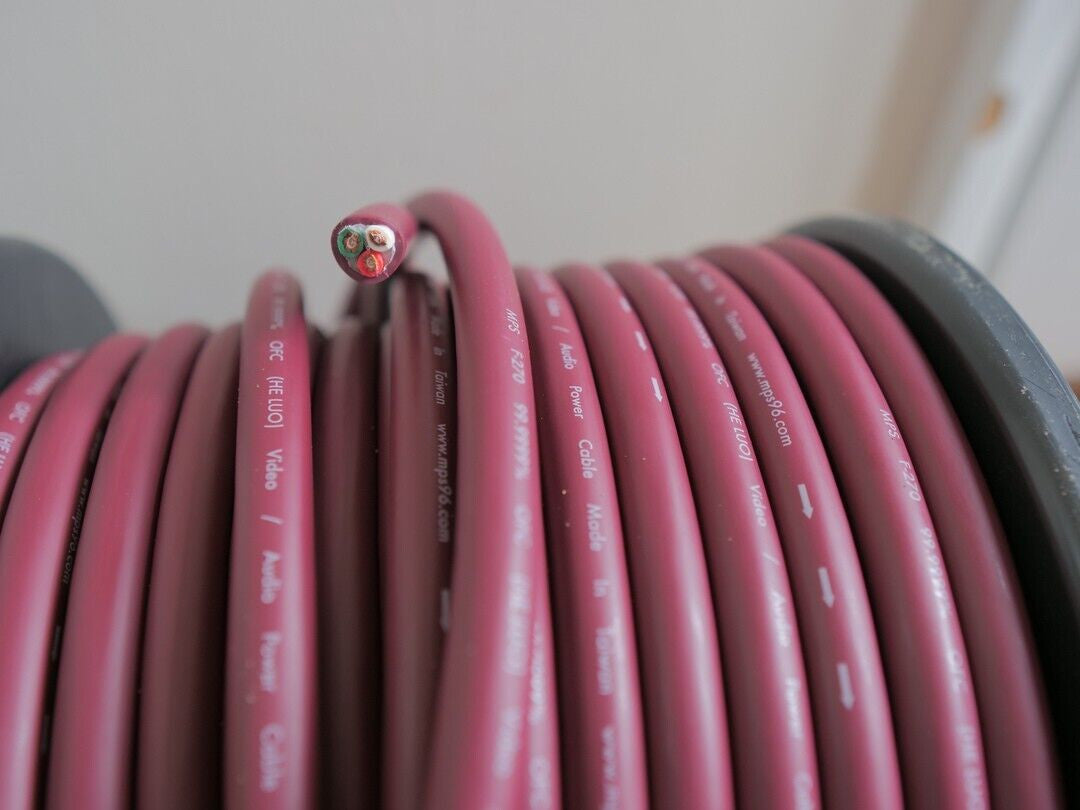 Coiled pink electrical cable close-up showing printed markings on the outer jacket