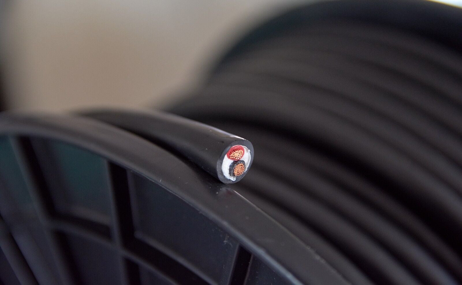 Black speaker cable with metal-tipped end and small red seal, close-up detail.