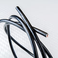 Black speaker cable with marked jacket and metal-capped ends, close-up view.