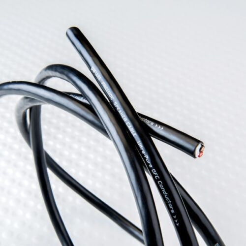Black speaker cable with marked jacket and metal-capped ends, close-up view.