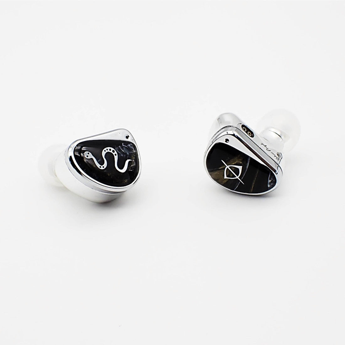 A pair of in-ear wireless earbuds with a polished silver-tone metallic finish and a glossy black faceplate featuring a white snake graphic and geometric logo, shown on a clean white background.