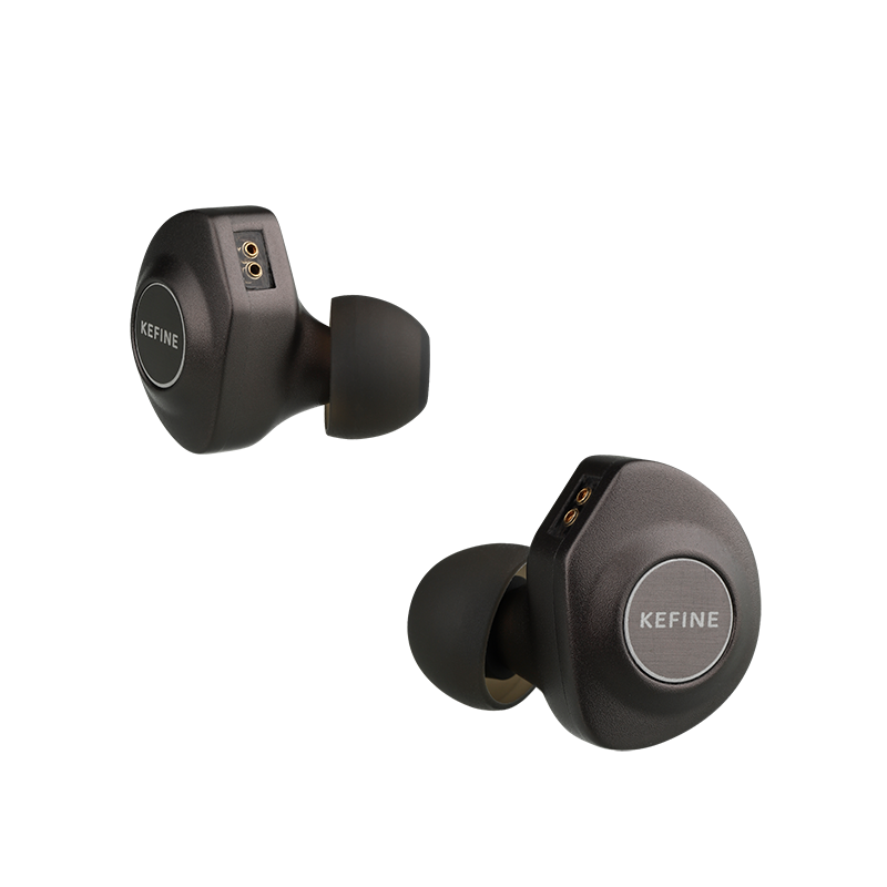Two KEFINE in-ear earbuds in a dark metallic gray finish with black silicone tips, shown from opposite angles on a solid white background.