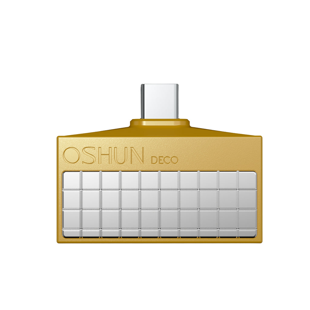 A gold rectangular UB C digital to analogue  converter  with a grid of small silver square tiles on the front and the embossed brand name 'OSHUN DECO' near the top left. The product is centered on a plain white background.