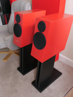Front view of two red loudspeakers with black drivers on black stands