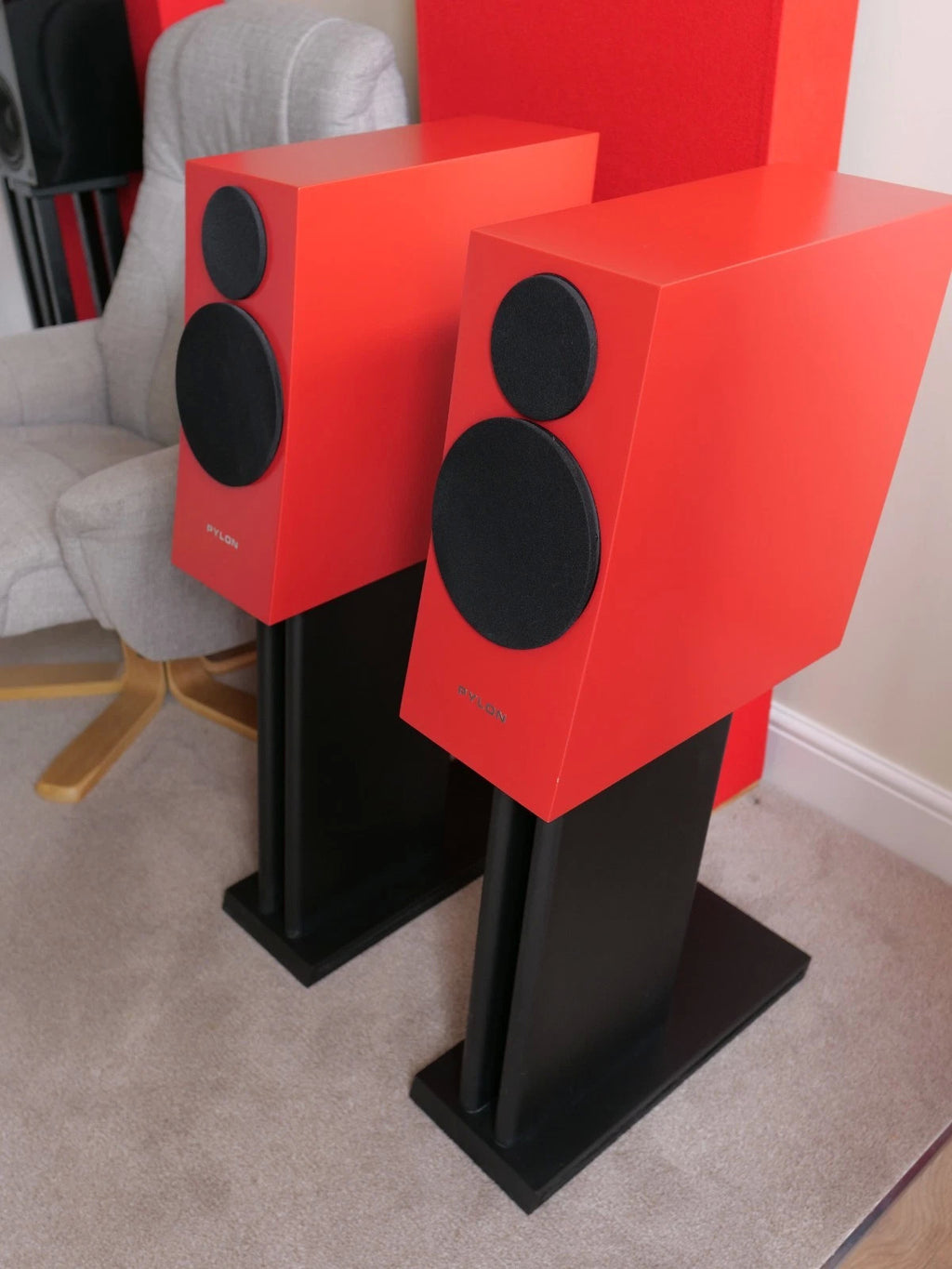 Red floor-standing speaker pair with black woofers and tweeter on black stands