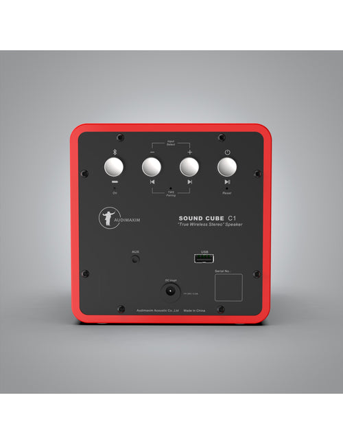 The rear view of the Audimaxim Sound Cube C1 wireless speaker in red and black, showing its control knobs, inputs, outputs, and ports against a gray gradient background.