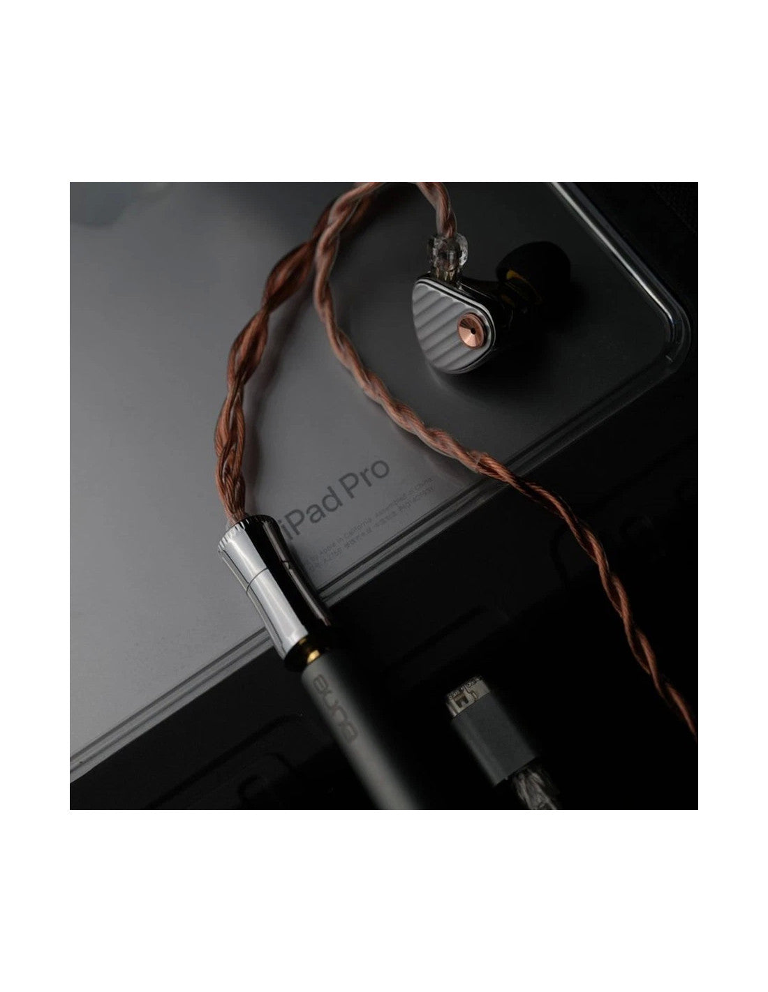 aune IR300 A close-up of a black in-ear monitor earpiece with a braided copper cable, connected to a matching wired earpiece and a USB-C cable, resting on a dark iPad Pro surface.