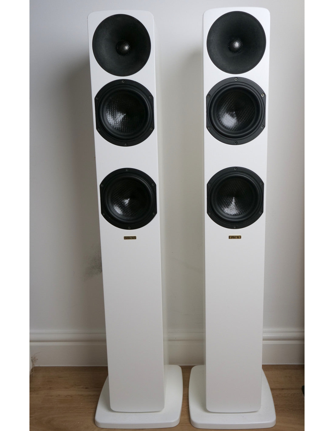 Satin white floorstanding loudspeaker pair with plinth bases and three black drivers per speaker