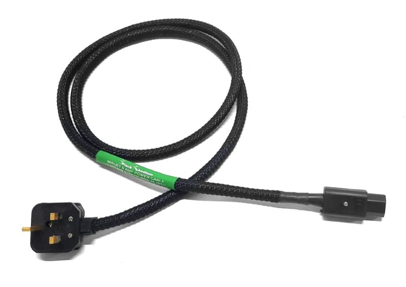 A black rhodium mains power cable with a UK three-pin plug on one end and a black connector on the other, featuring a green label in the center.
