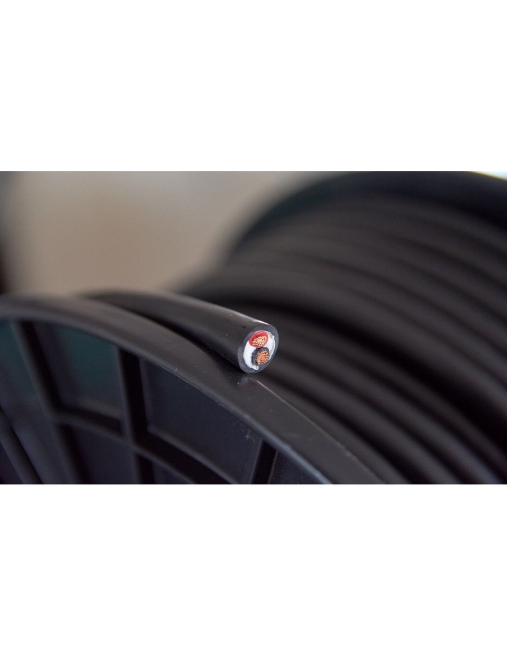 Black speaker cable jacket with small red-and-white badge detail