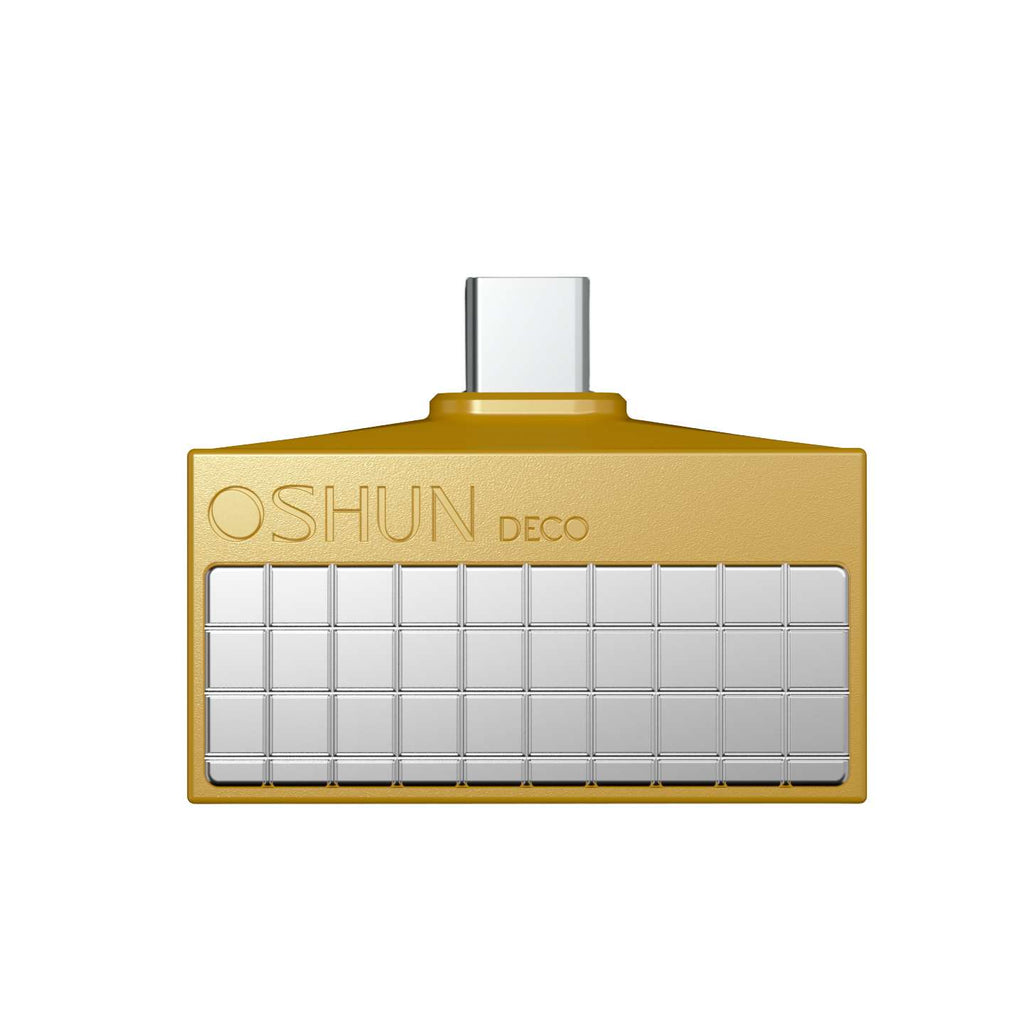 A gold rectangular UB C digital to analogue  converter  with a grid of small silver square tiles on the front and the embossed brand name 'OSHUN DECO' near the top left. The product is centered on a plain white background.