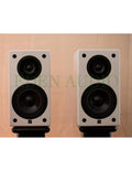Gloss white bookshelf loudspeakers, two woofers and tweeter per speaker, angled front