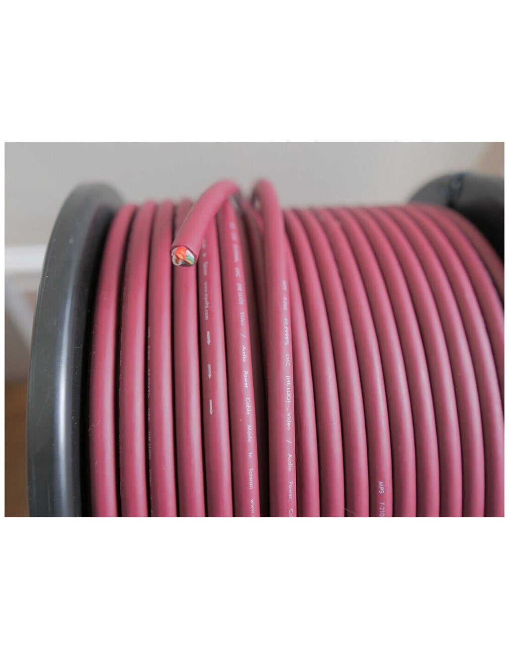 Maroon power cable coil on reel, looped jacket with small printed markings